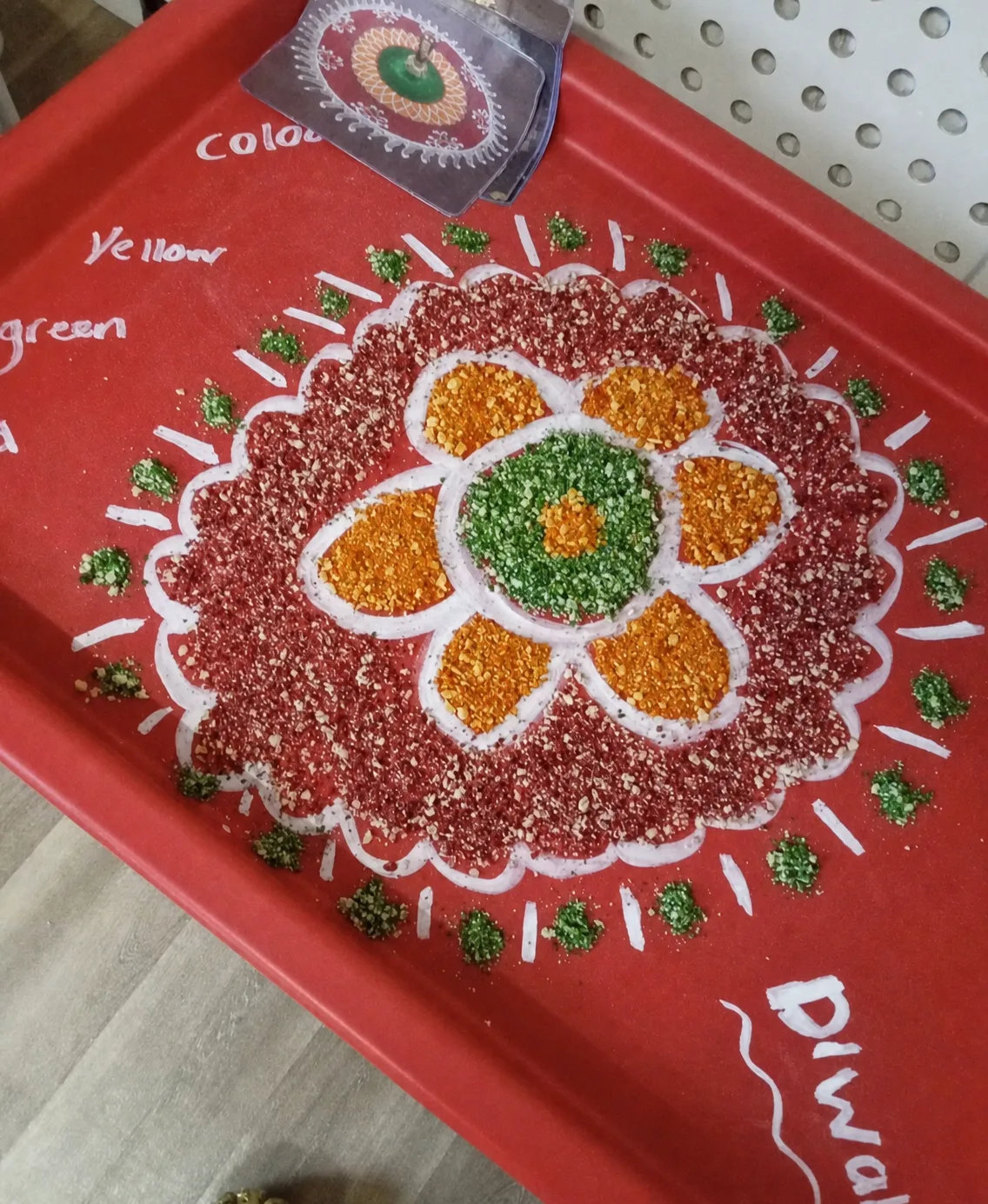 A colourful rangoli-inspired sensory pattern arranged on a red tray