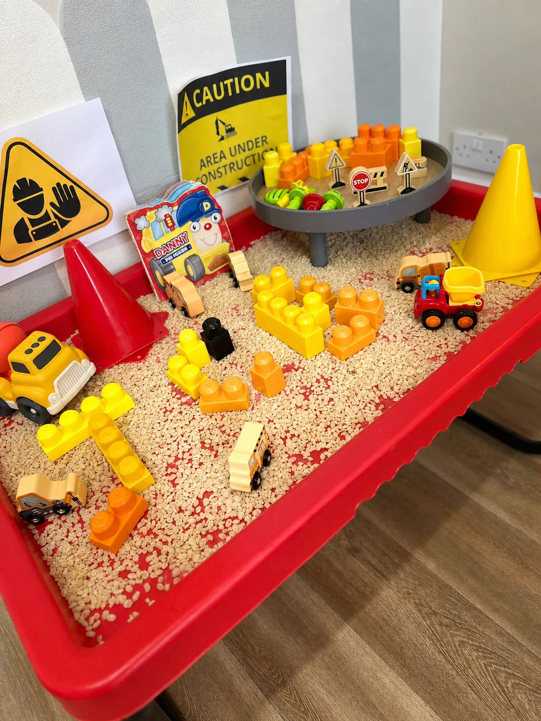 A construction-themed sensory tray with toy vehicles, blocks and textured materials