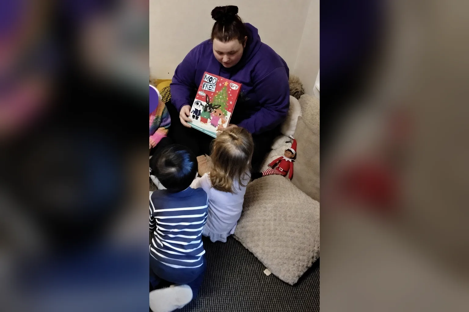 A nursery practitioner sharing a picture book with a small group of children