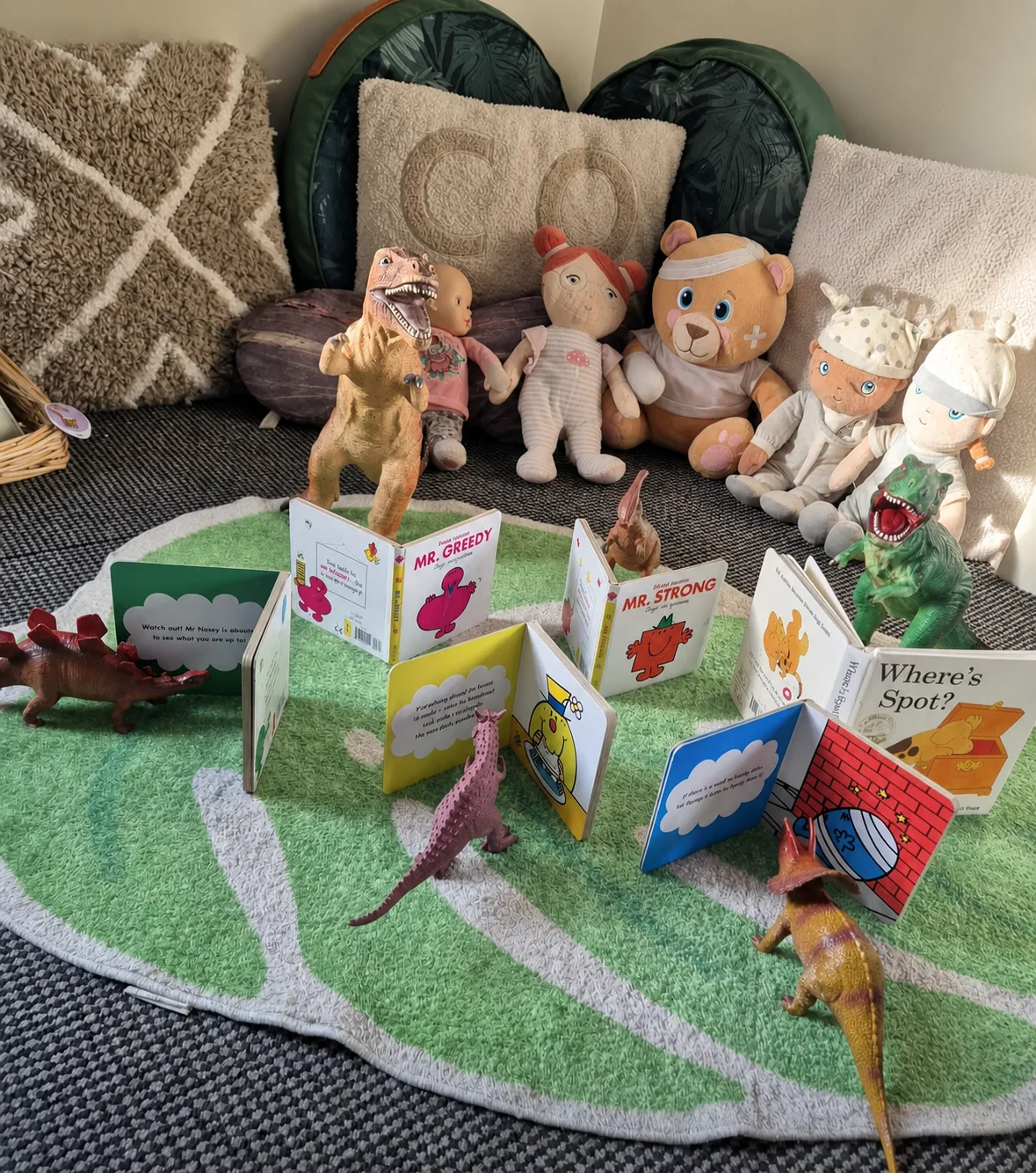 Childrens storybooks displayed with matching soft toy characters in a cosy reading area