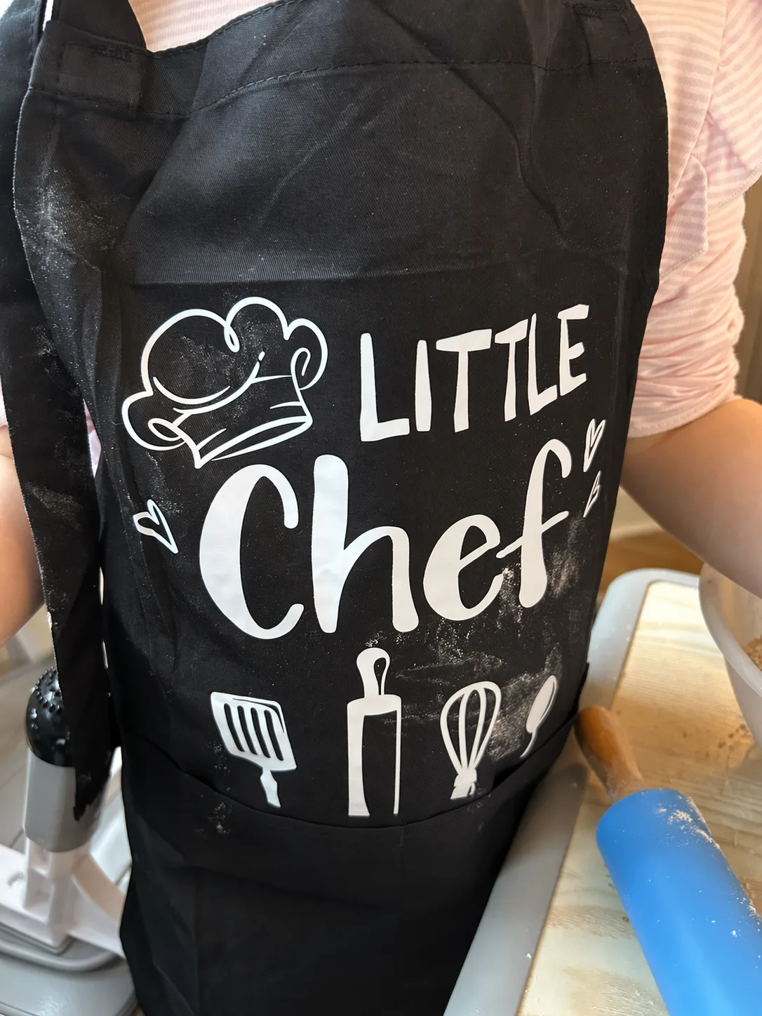 A child wearing a Little Chef apron during a nursery cooking activity